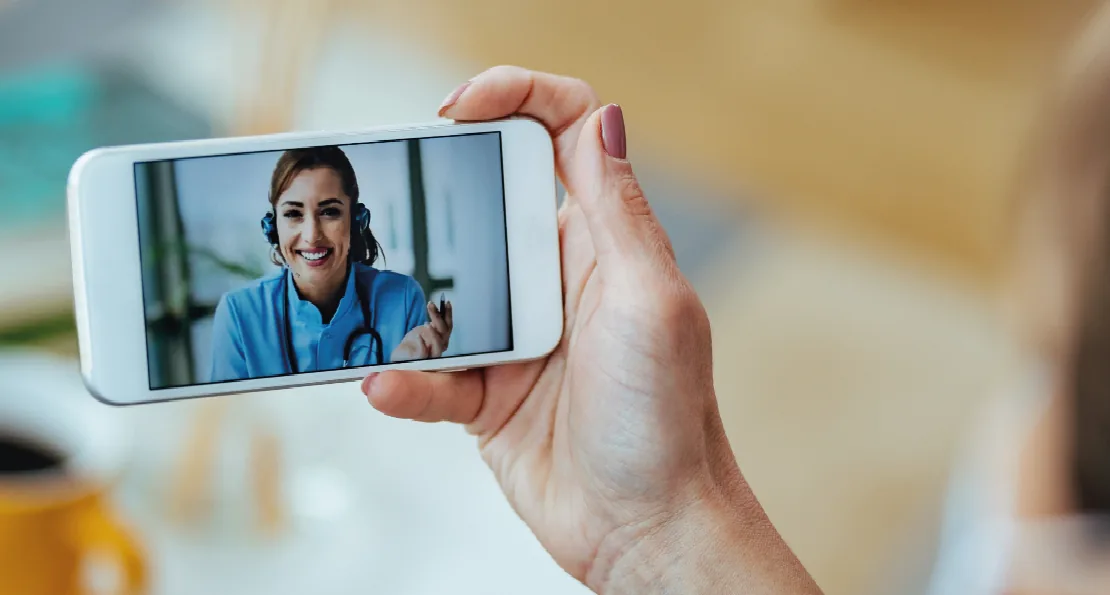 Mão segurando celular em uma videochamada com uma médica